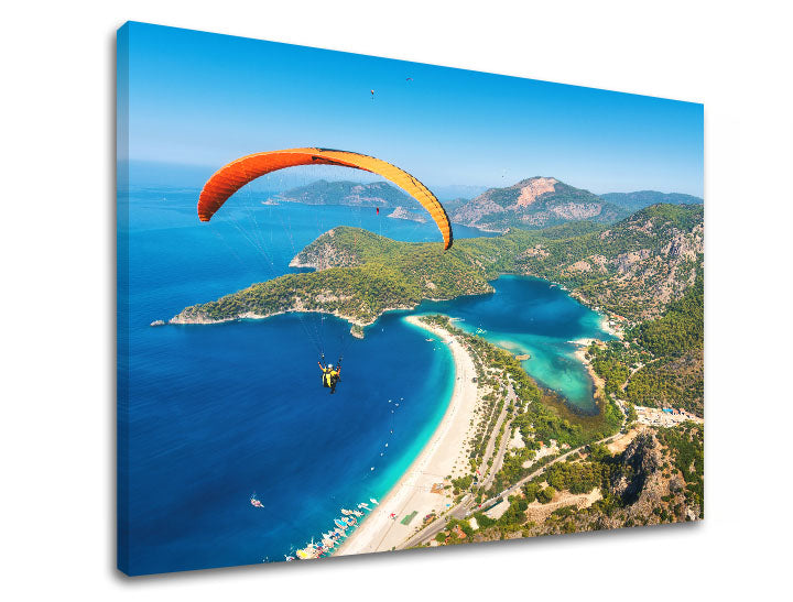 Slika na platnu z motivom padalec nad modro laguno in plažo – 3D prikaz platna z vidnim lesenim okvirjem, Papilora.